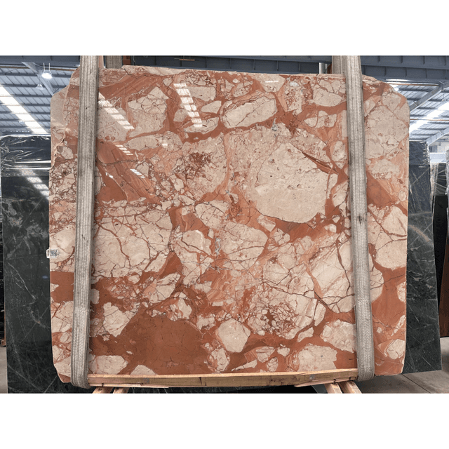 Red and grey natural stone slabs stacked against a wall