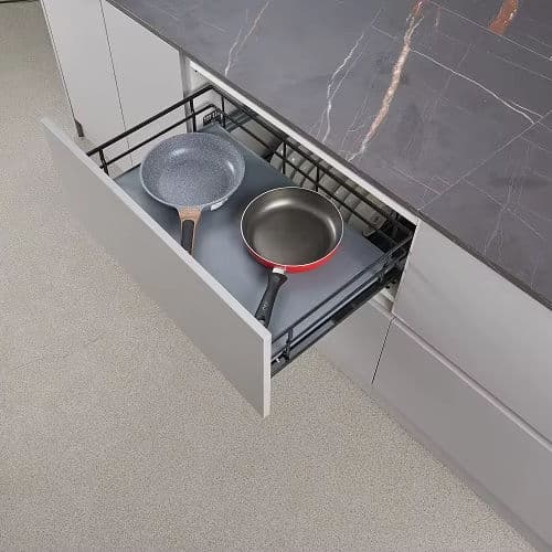 Pull-out basket drawer holding pans beneath a stone worktop